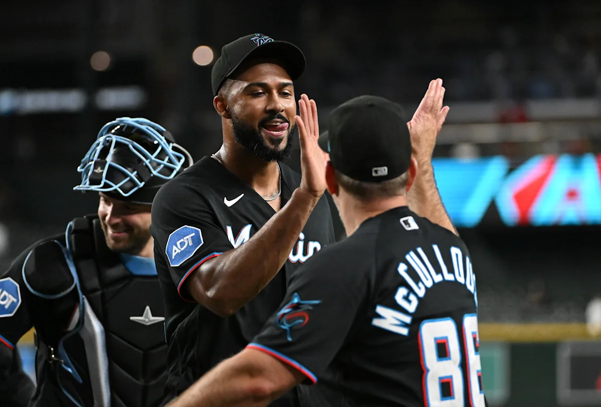 Marlins players high-five near home plate during a baseball game