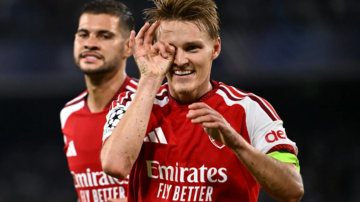 Arsenal player celebrates with an eye gesture as a teammate stands behind him on the pitch