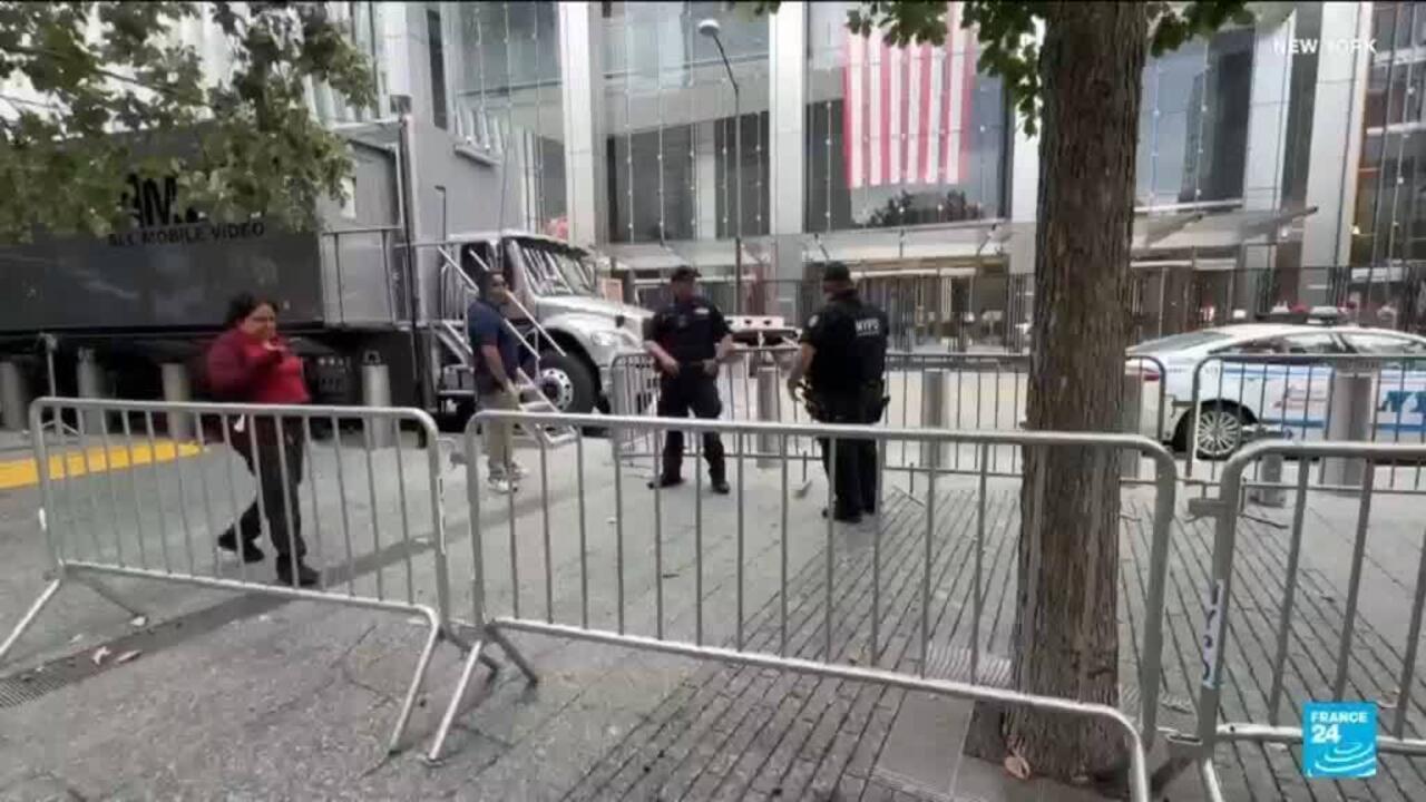 Police officers and security barriers outside a modern building, with a truck and police car nearby.