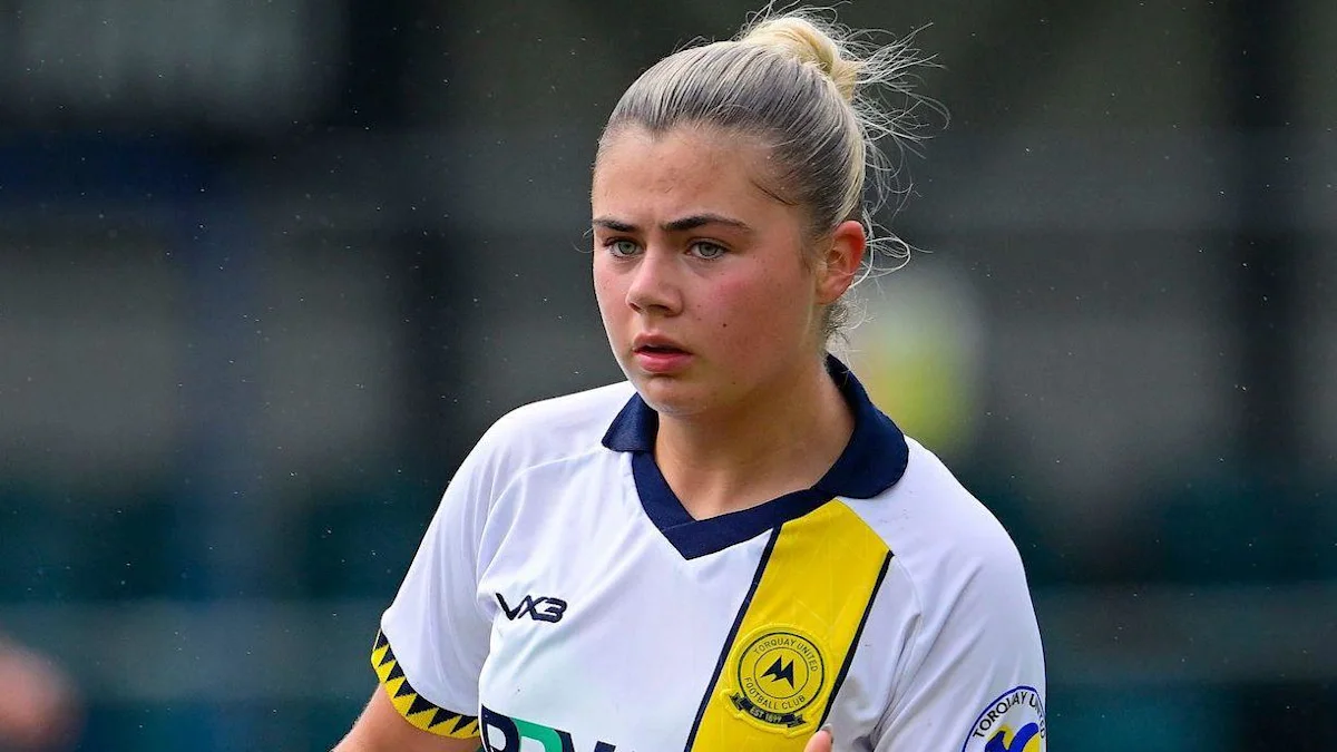 Young woman footballer in a white and yellow jersey on the pitch.