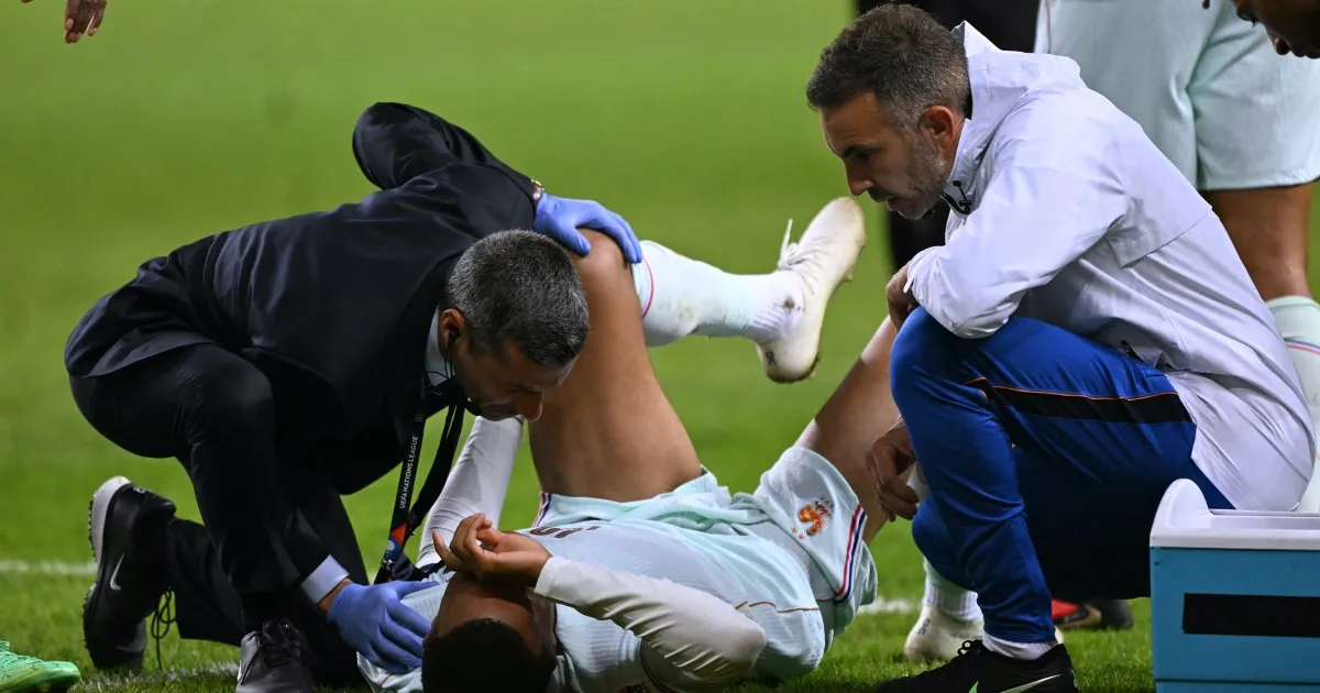 Medical staff attend to a football player lying on the pitch during a match.
