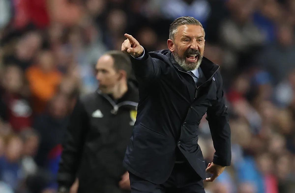 Football manager shouting and pointing from the touchline during a match