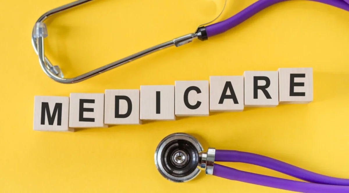 Stethoscope and letter tiles spelling MEDICARE on a bright yellow background
