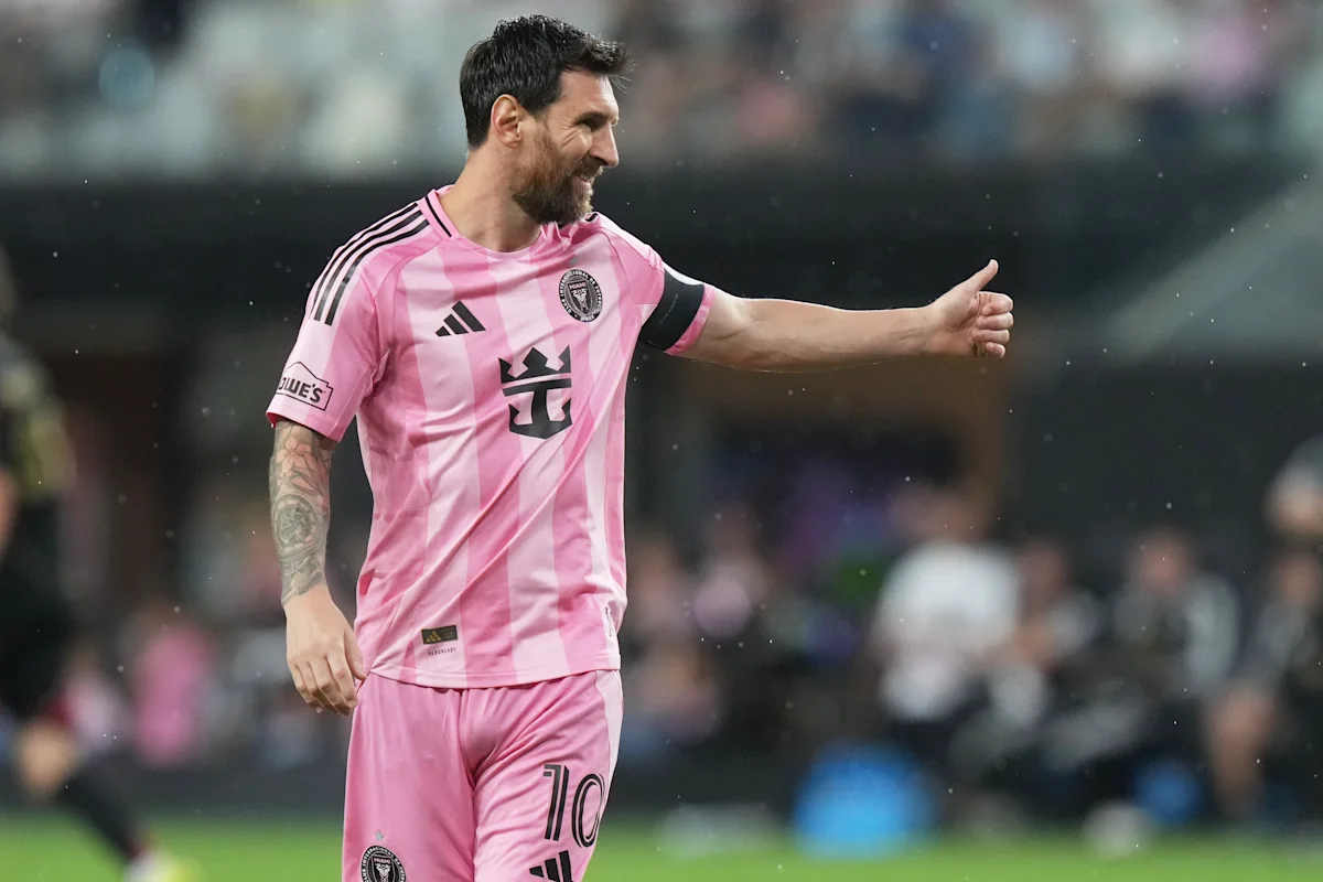 Footballer in pink Inter Miami jersey gestures during a match amid falling rain