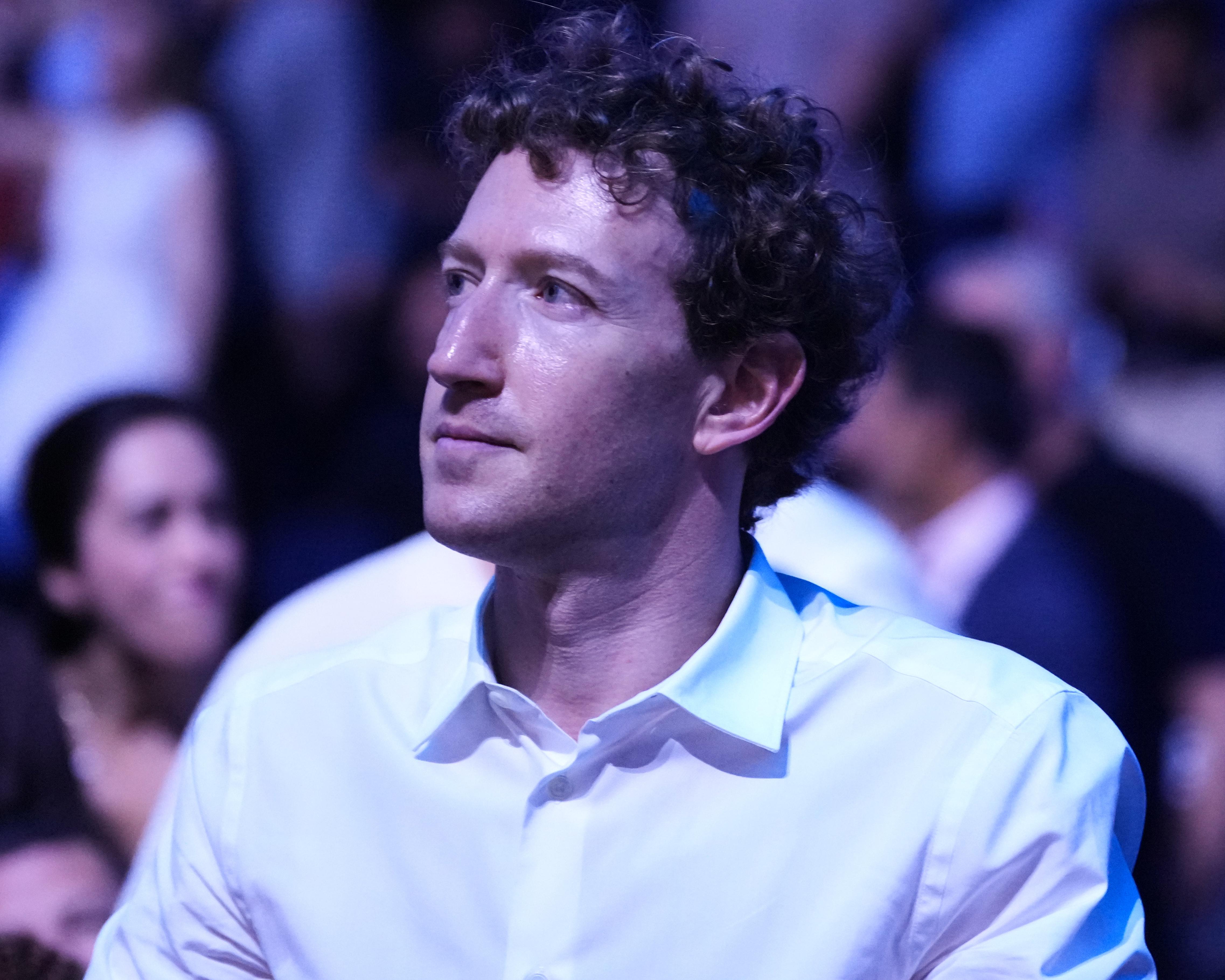 Man in white shirt seated under blue and purple lighting at an event