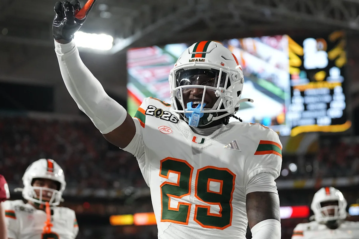 Miami football player wearing number 29 raises a gloved hand during a nighttime game.