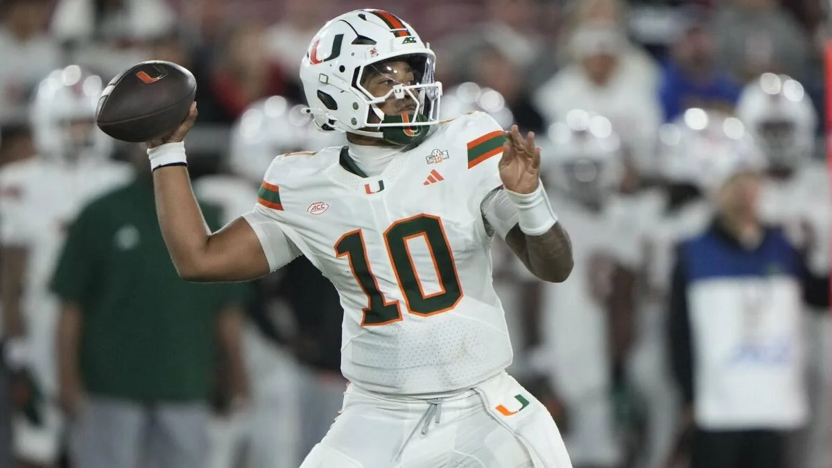 Miami quarterback in white uniform and helmet prepares to throw a football during a game.