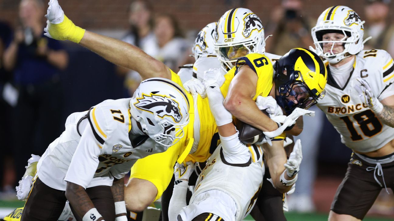 Football players in yellow and white uniforms collide during a close defensive play.
