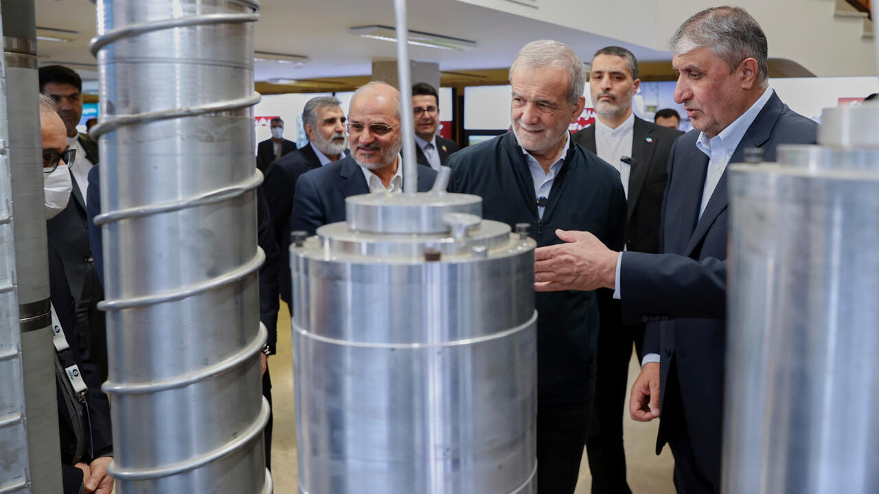 Officials stand among large cylindrical metal machinery during a formal exhibition or inspection.