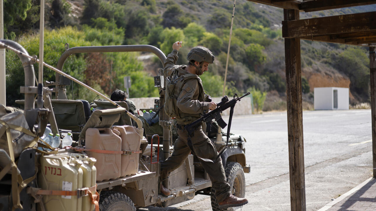 Israeli soldier carrying a rifle steps from a military utility vehicle loaded with equipment
