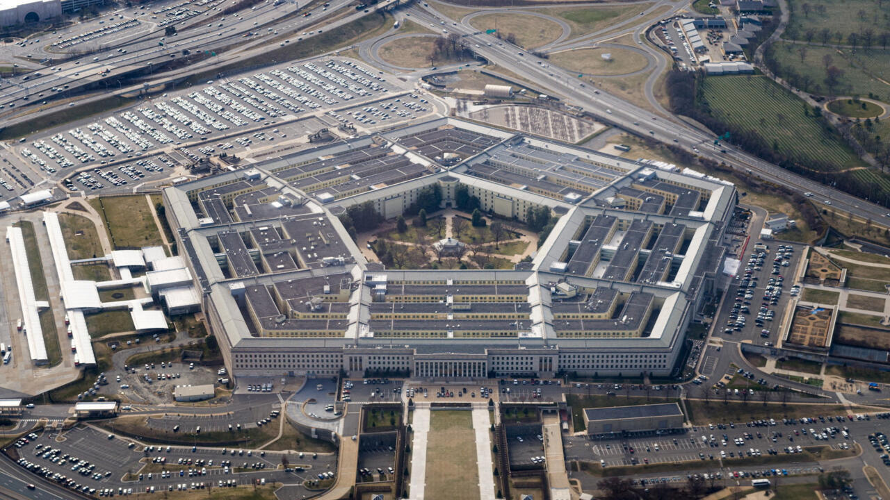 Aerial view of a large Pentagon-style complex surrounded by highways, parking lots, and landscaped grounds.