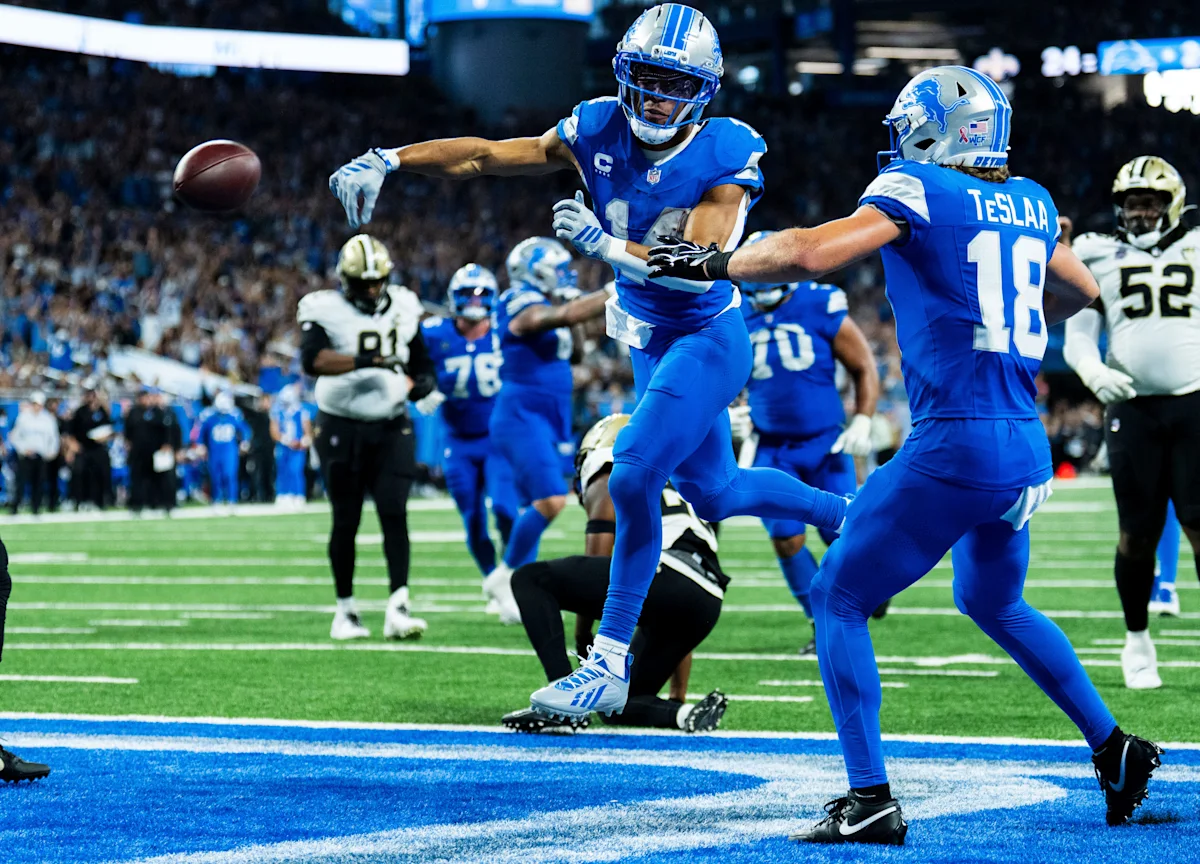Detroit Lions players celebrate a touchdown as teammates run across the end zone.