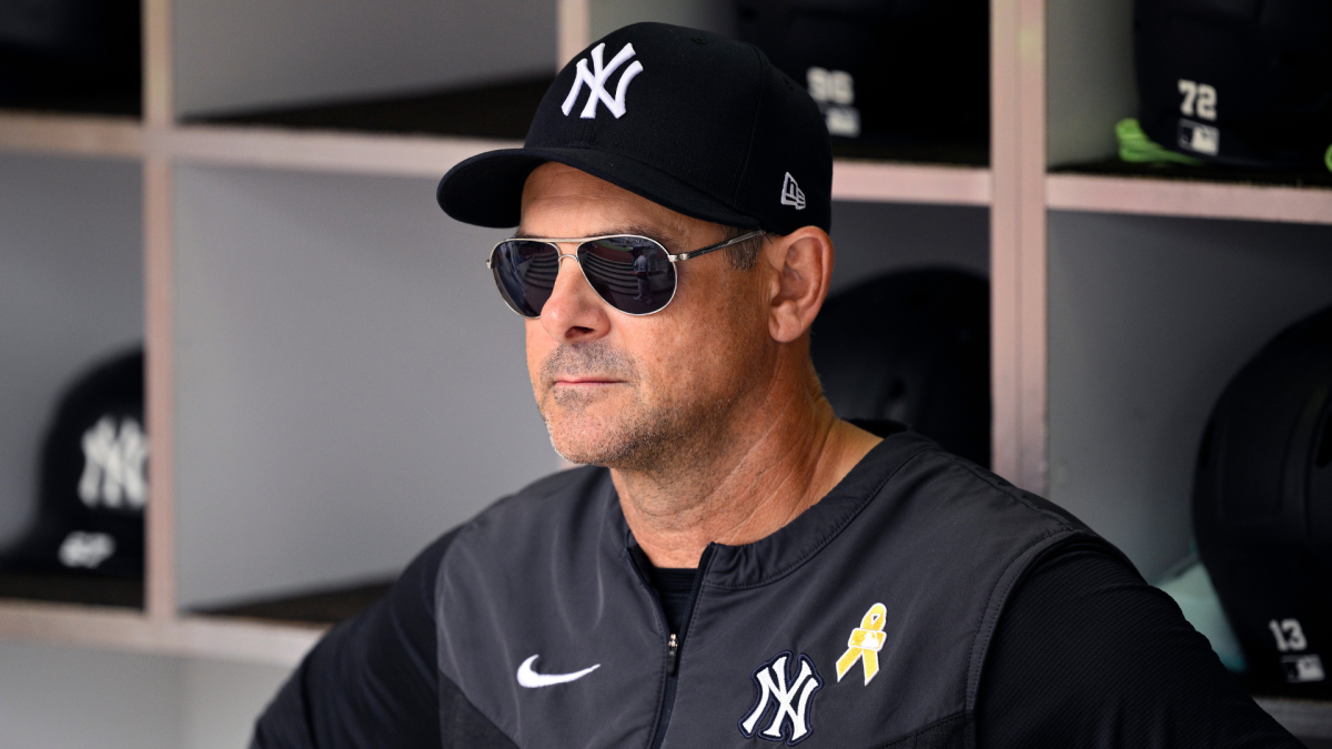 Man in Yankees cap and sunglasses seated in a baseball clubhouse dugout area