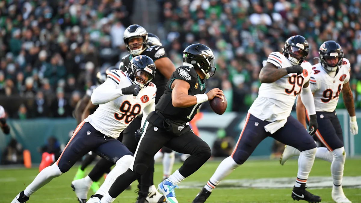 Eagles quarterback runs with the ball as Bears defenders pursue during an NFL game.