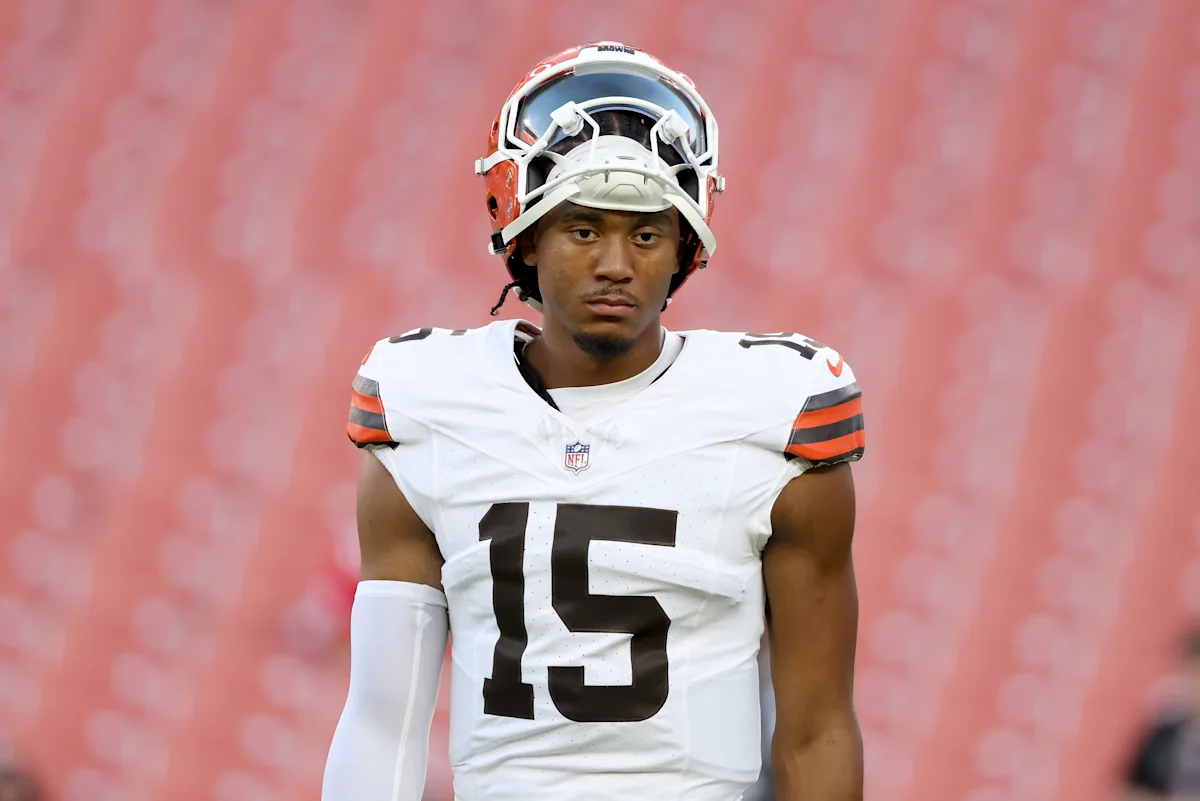 Cleveland Browns football player wearing number 15 stands in uniform with helmet raised.