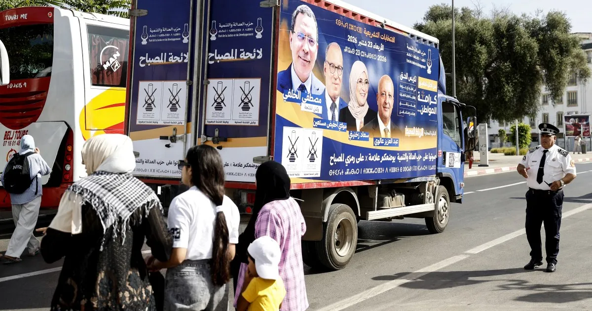 Election campaign truck displaying Moroccan party posters beside pedestrians and a uniformed traffic officer