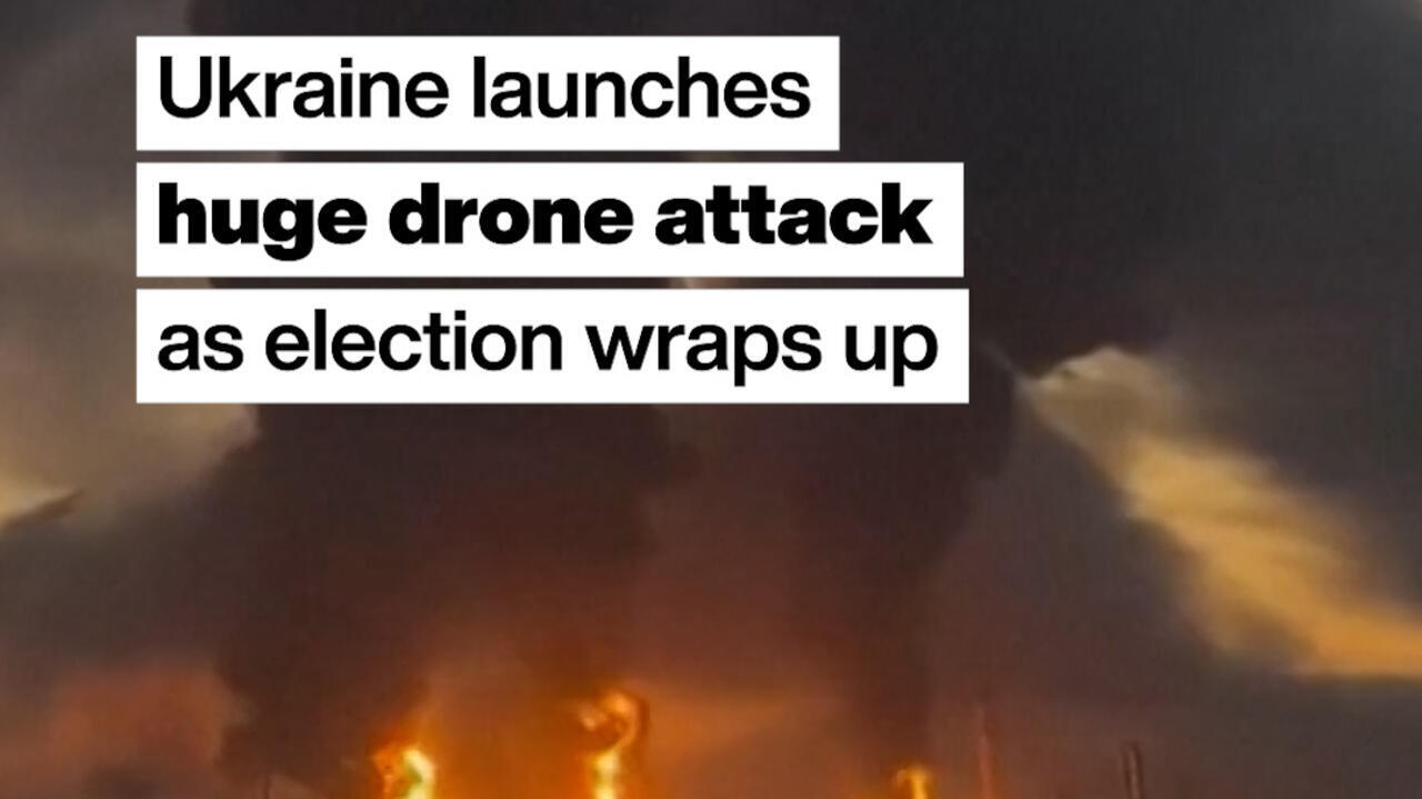Nighttime scene with flames and thick smoke beneath bold text about a Ukrainian drone attack.