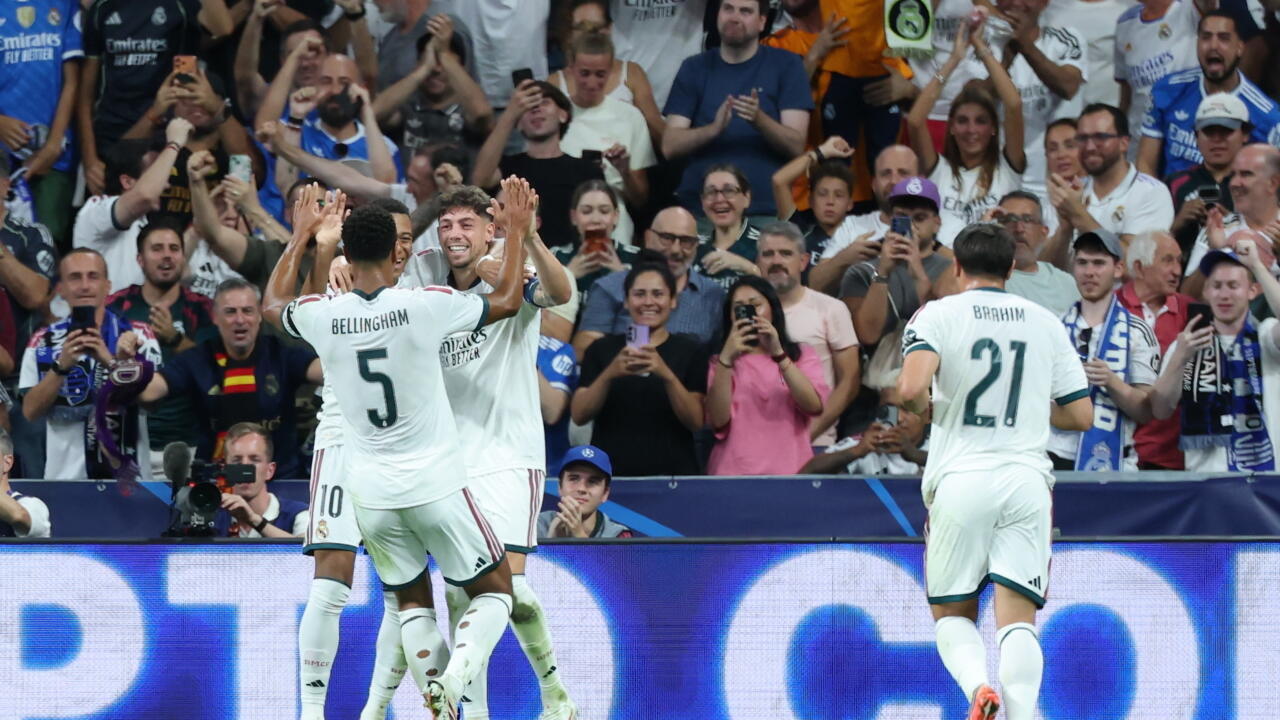 Real Madrid players celebrate in front of cheering supporters during a Champions League match.