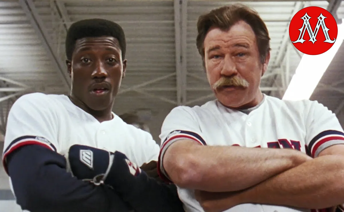 Two baseball players in white uniforms stand together inside a stadium or sports facility