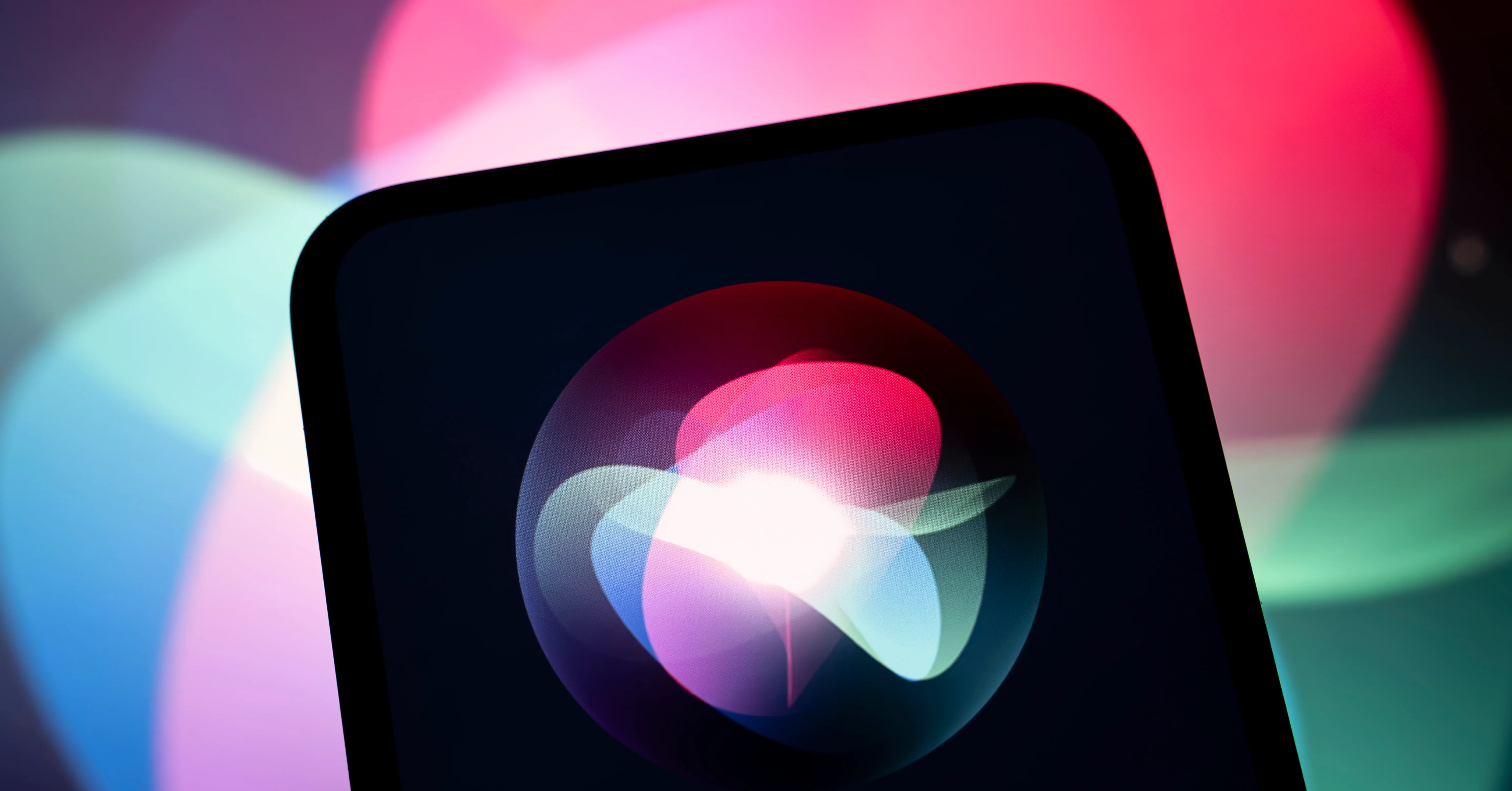 Tablet displaying a colorful Siri-like abstract icon against a blurred neon pink, blue and green background