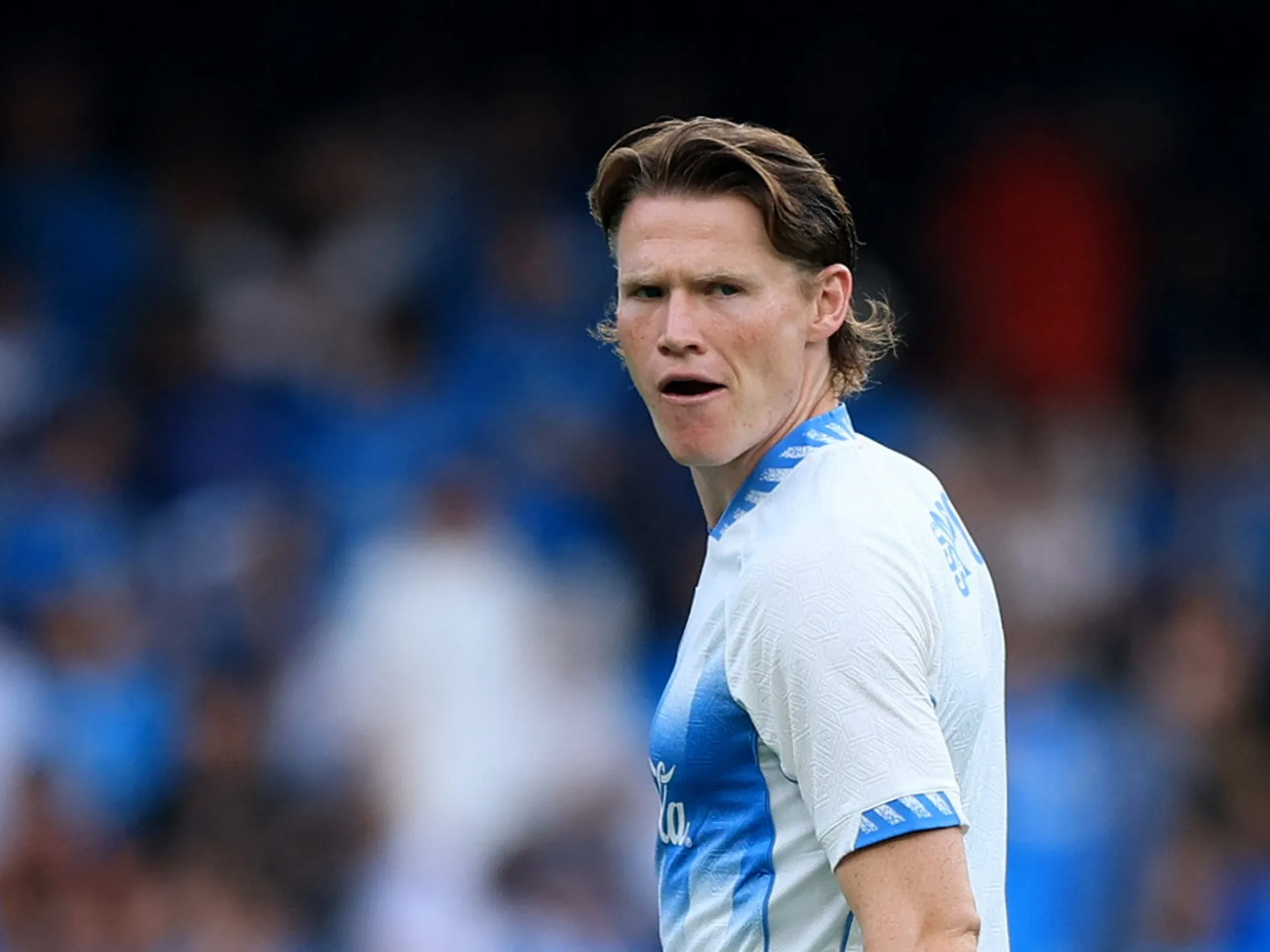 Footballer in white and blue jersey looking over his shoulder during a match