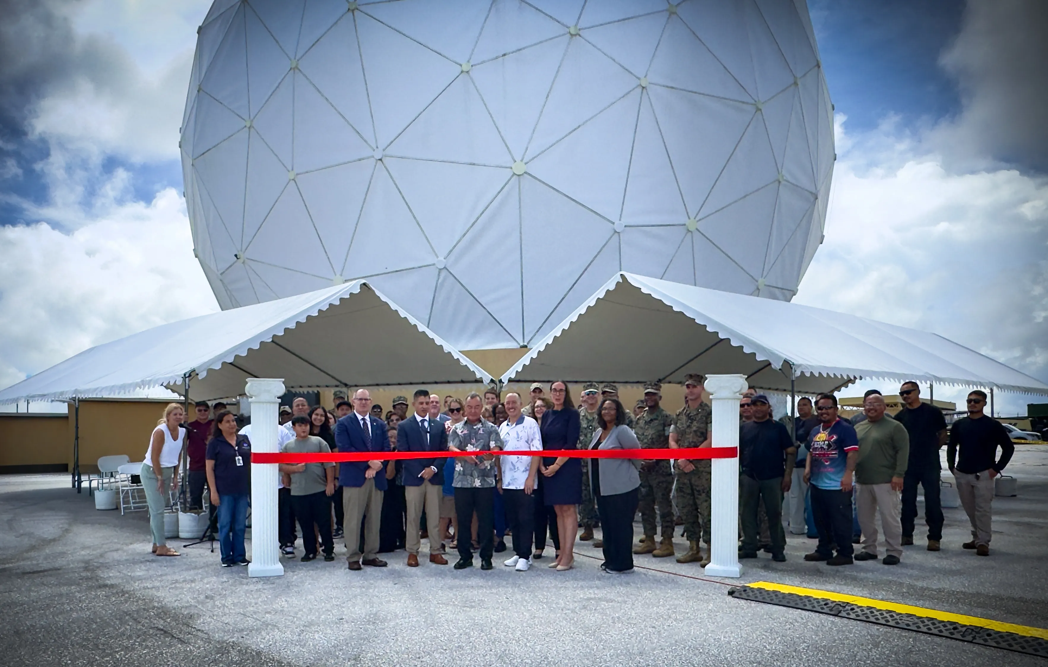 Group gathered beneath a large geodesic dome for a ribbon-cutting ceremony.
