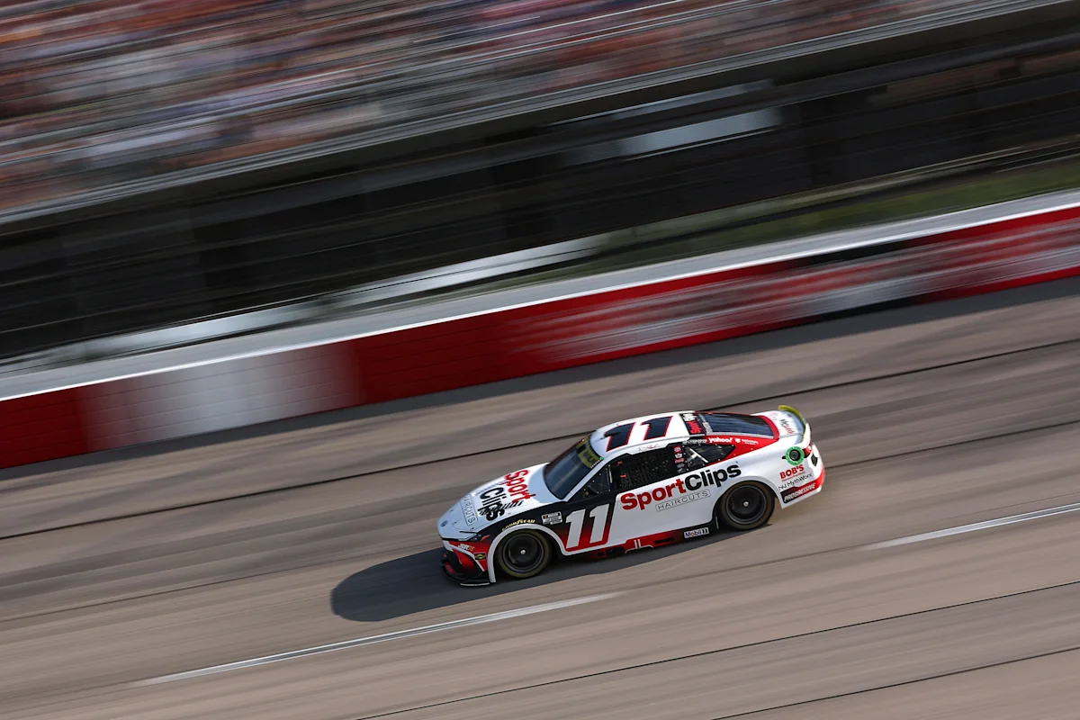 NASCAR stock car number 11 racing along a track beside red and white barriers