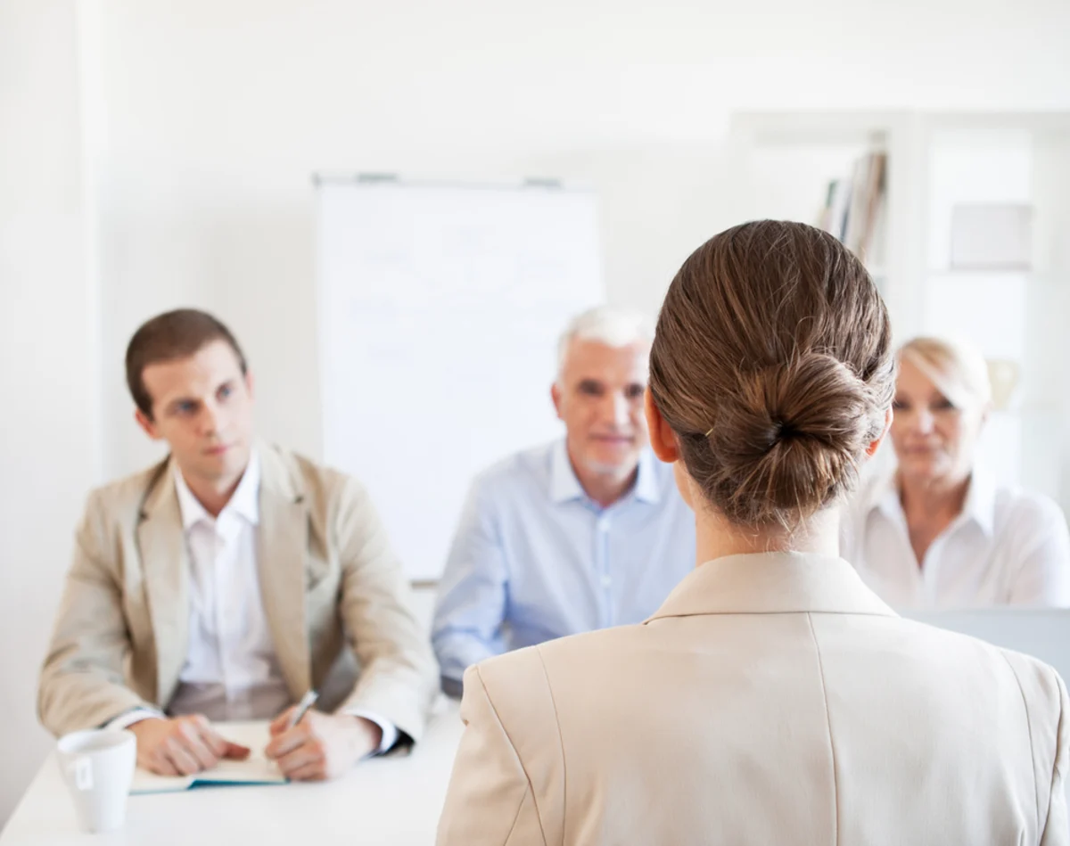 Businesswoman addressing three colleagues seated around a table in a bright office meeting room