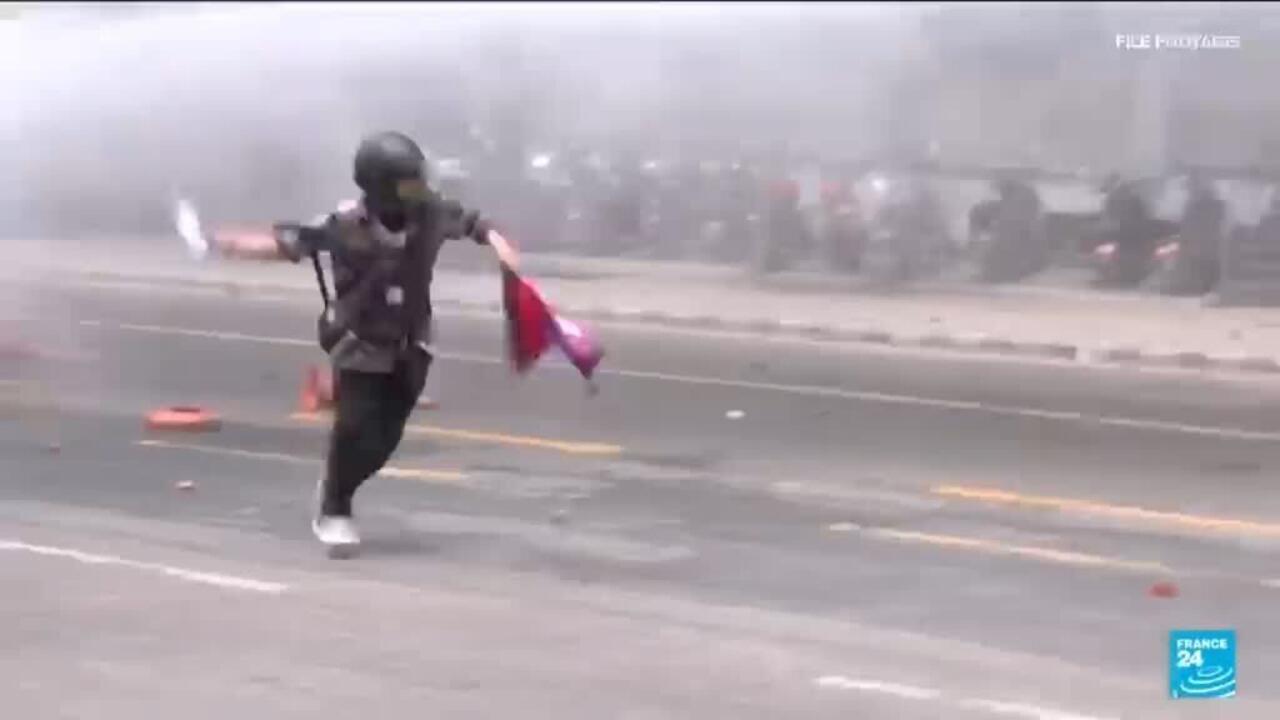 Person runs across a smoke-filled roadway carrying a red and blue flag.