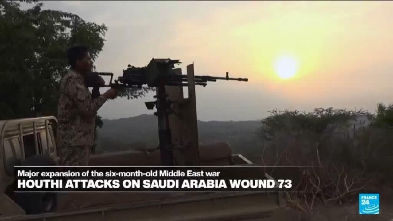 Armed man stands on a vehicle-mounted gun overlooking hills at sunset.