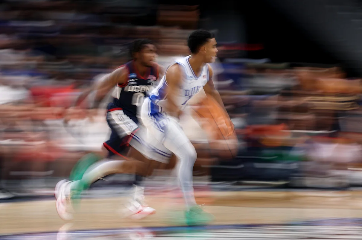 Basketball players in Duke and UConn uniforms sprint during a blurred game action sequence.