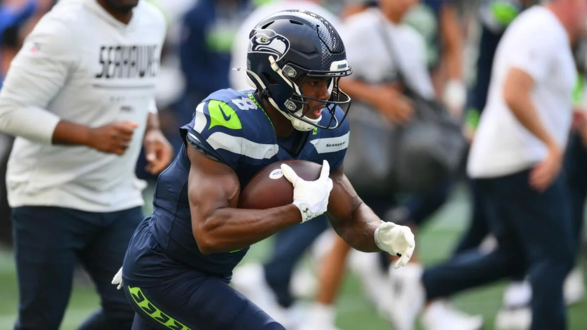 Seattle Seahawks player in helmet runs with a football during game action