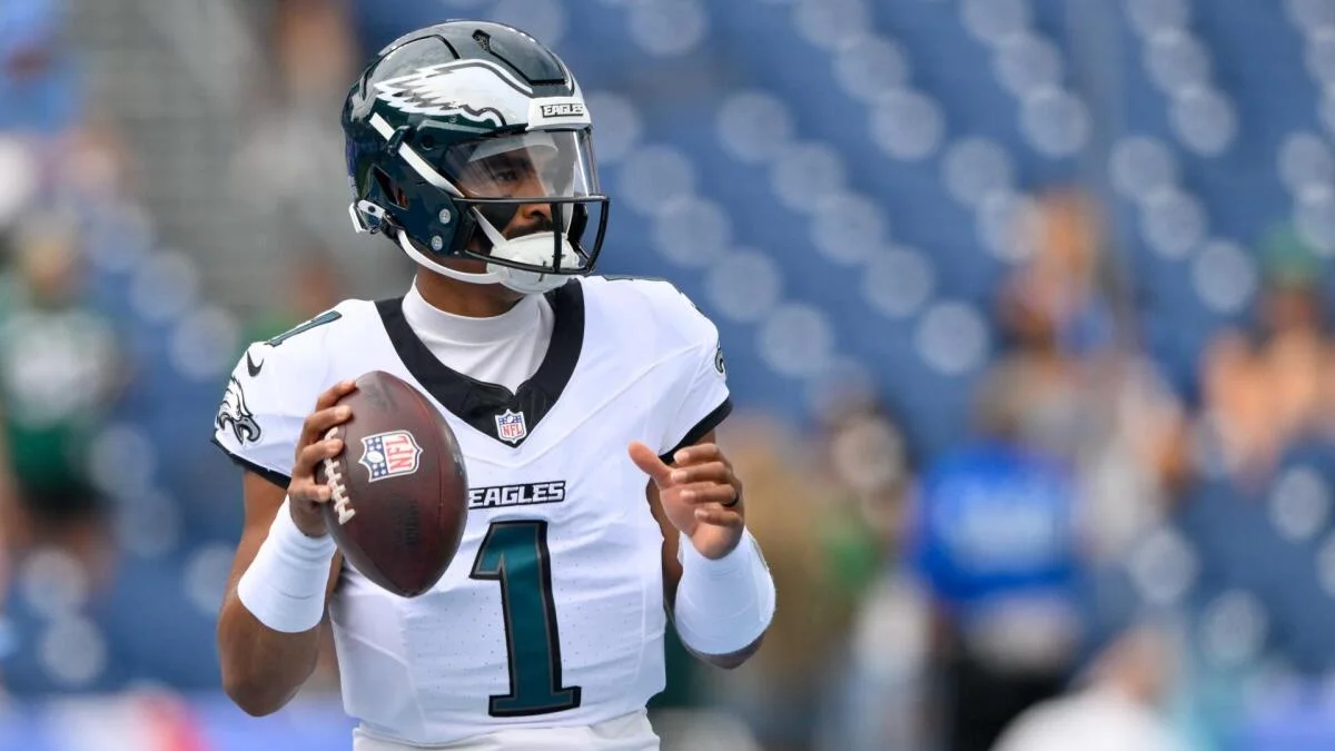 Philadelphia Eagles player in a white uniform holds a football on the field.