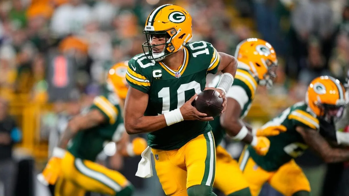 Green Bay Packers quarterback in a yellow helmet holds the football during a game.