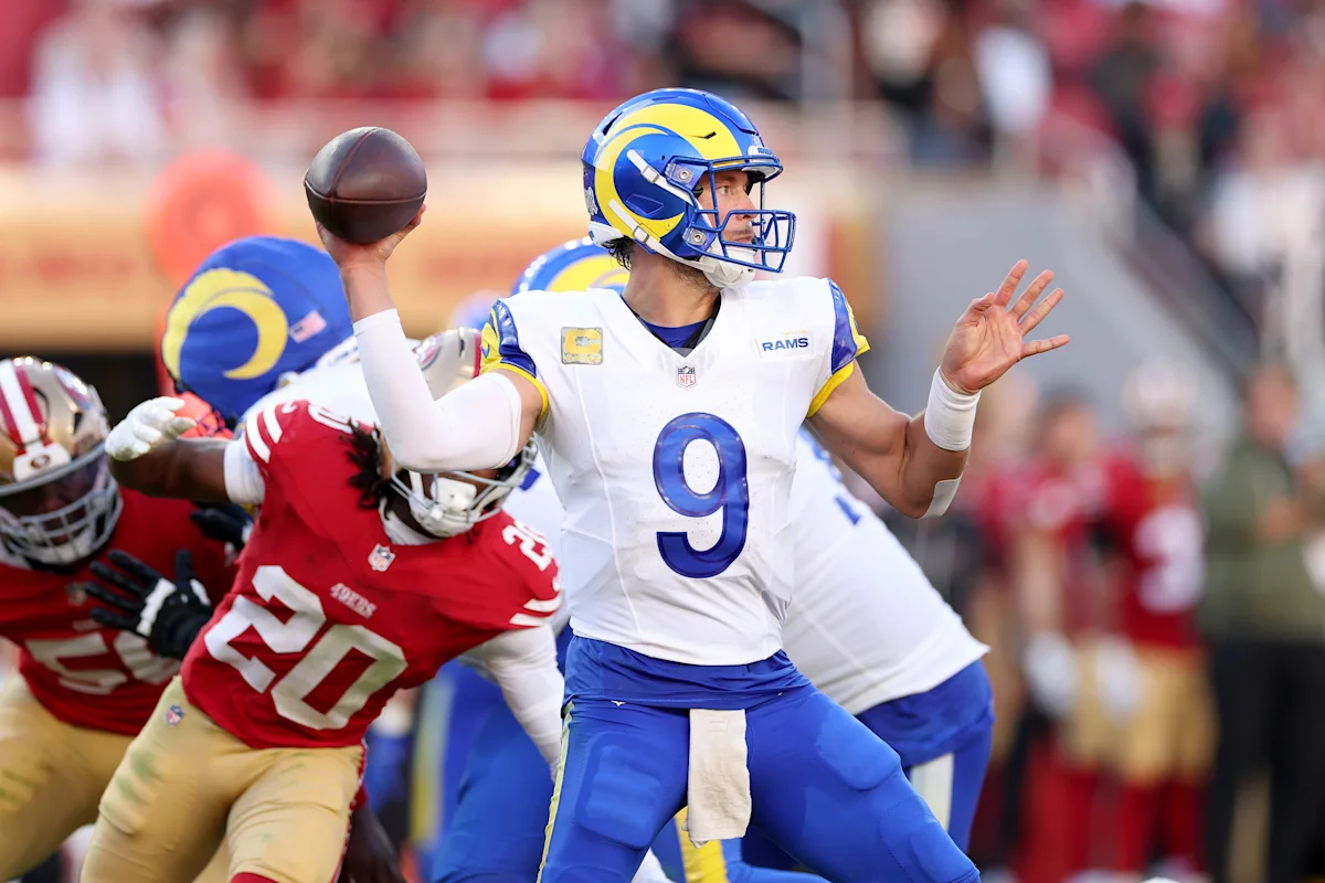 Rams quarterback throws a pass as a 49ers defender pressures him during an NFL game