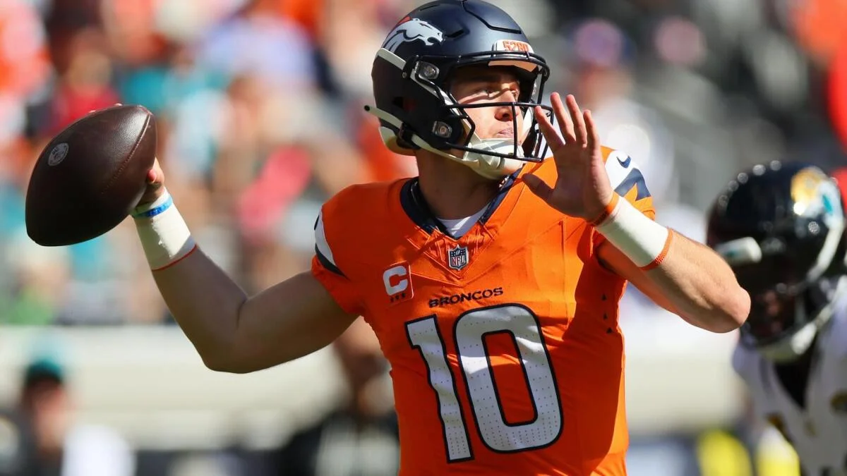 Denver Broncos quarterback in an orange number 10 jersey prepares to throw a football.