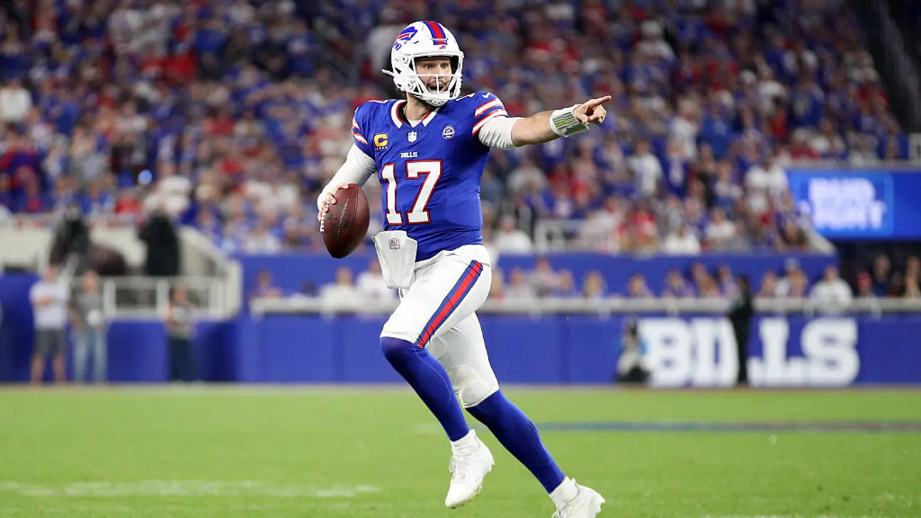 Football player in a blue number 17 uniform prepares to throw a pass on the field.