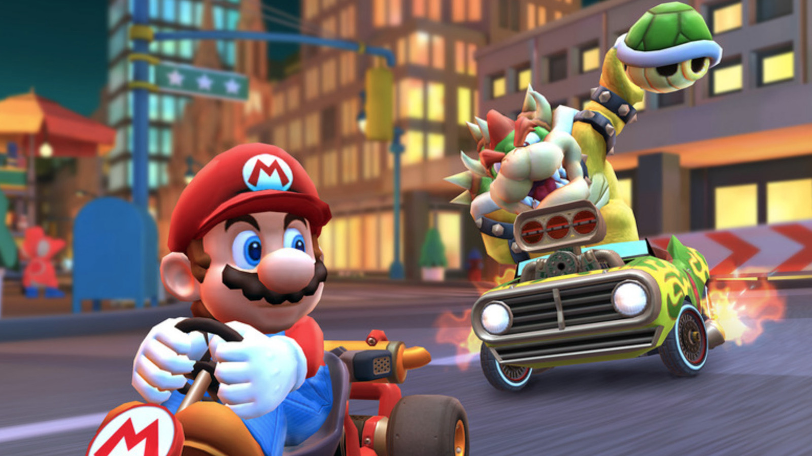 Mario drives a kart as Bowser and a masked racer follow in a brightly lit city race.