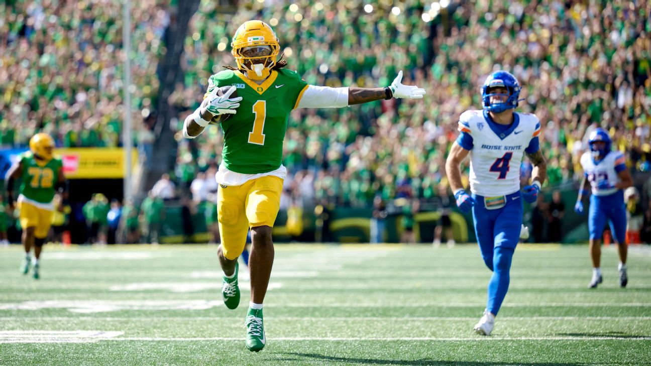 Oregon football player runs with arms extended as Boise State defenders pursue.