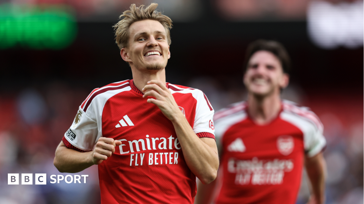 Arsenal footballer smiling and running in red and white kit during a match