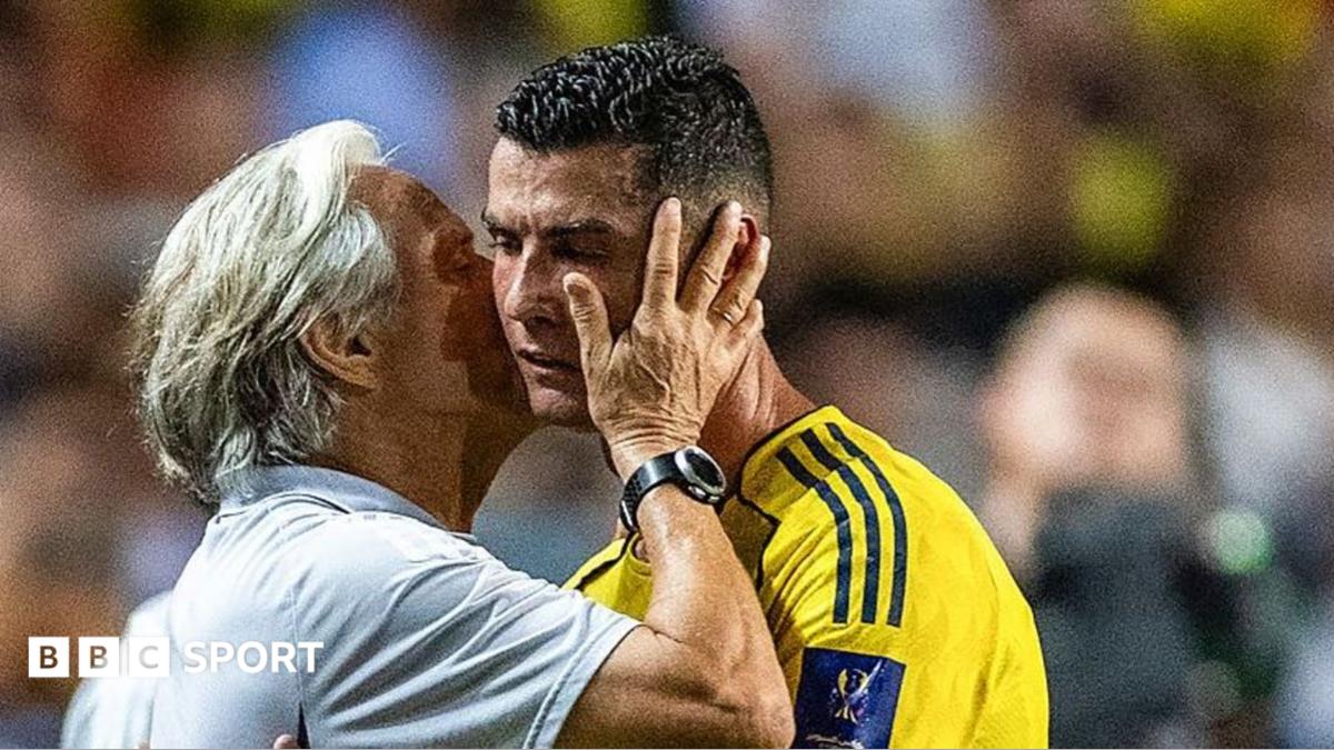 An older man cups a footballer’s face as the player in a yellow jersey looks ahead.