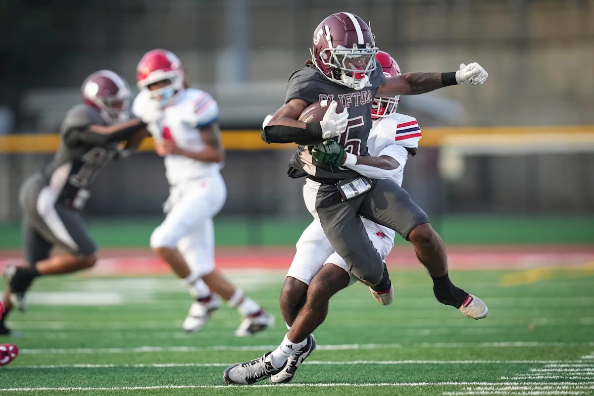 High school football player in maroon and gray uniform evades a defender on the field