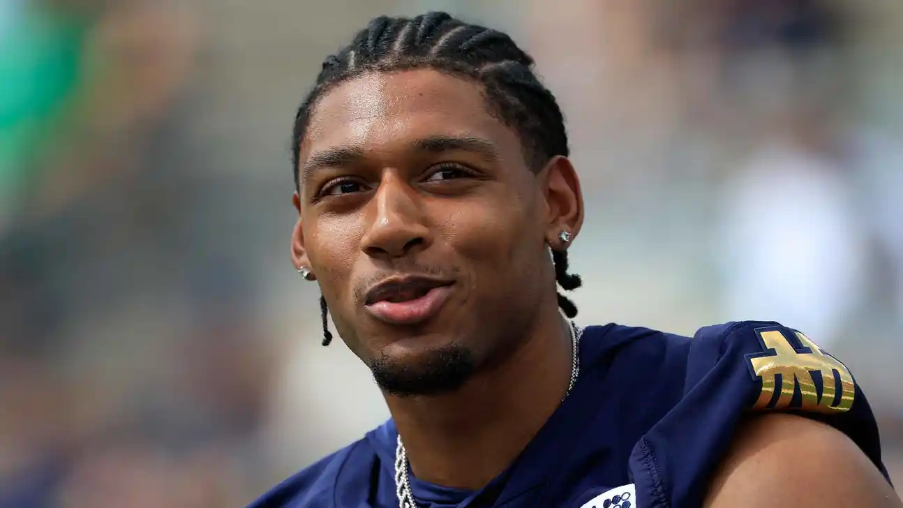 Close-up of a football player wearing a navy jersey with gold lettering and shoulder detailing.