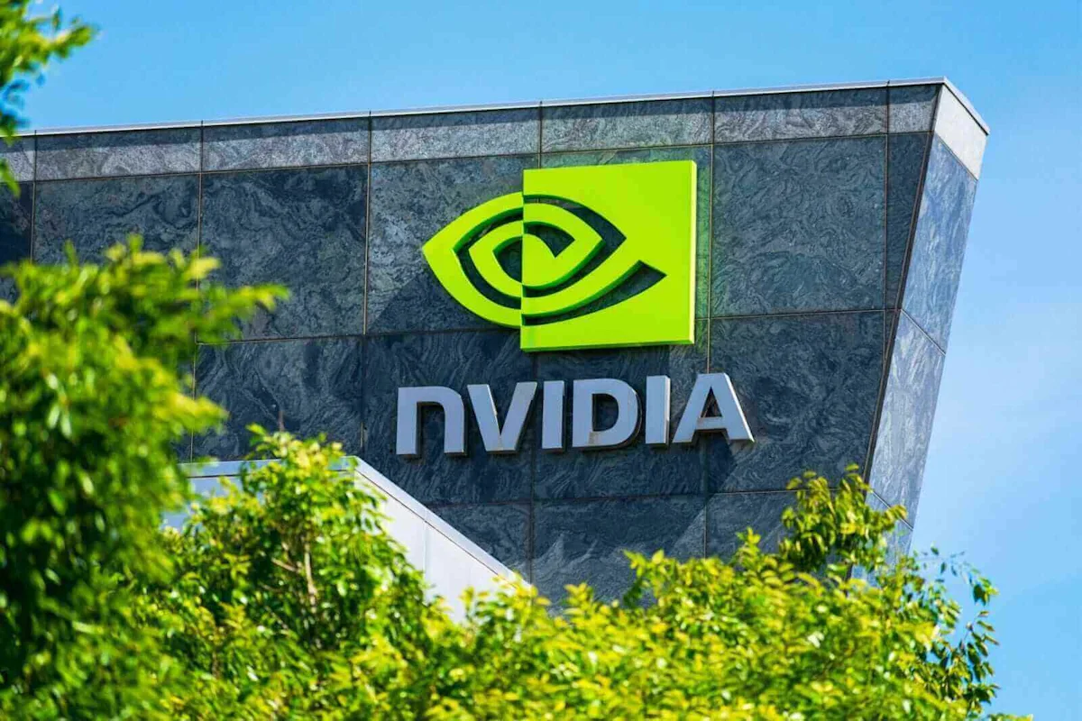Nvidia logo and lettering displayed on a dark building facade behind leafy trees