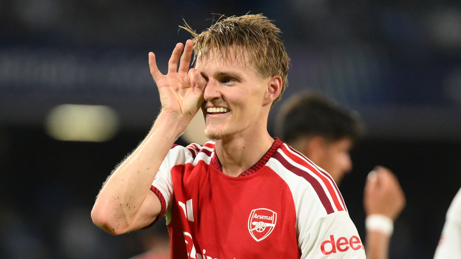 Arsenal player in red jersey celebrates by making a circle gesture around his eye.