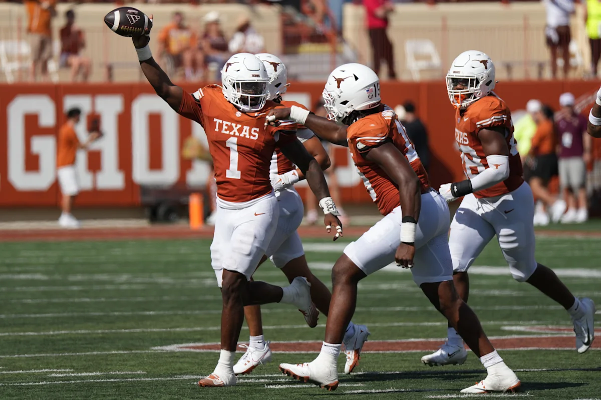 Texas football players in orange uniforms celebrate as a teammate raises the ball during a game.