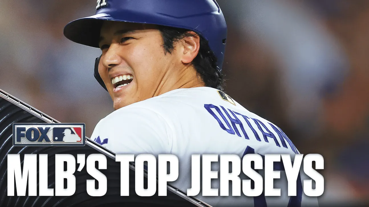 Smiling baseball player in a white jersey and blue helmet, with a broadcast graphic reading “MLB’s Top Jerseys.”