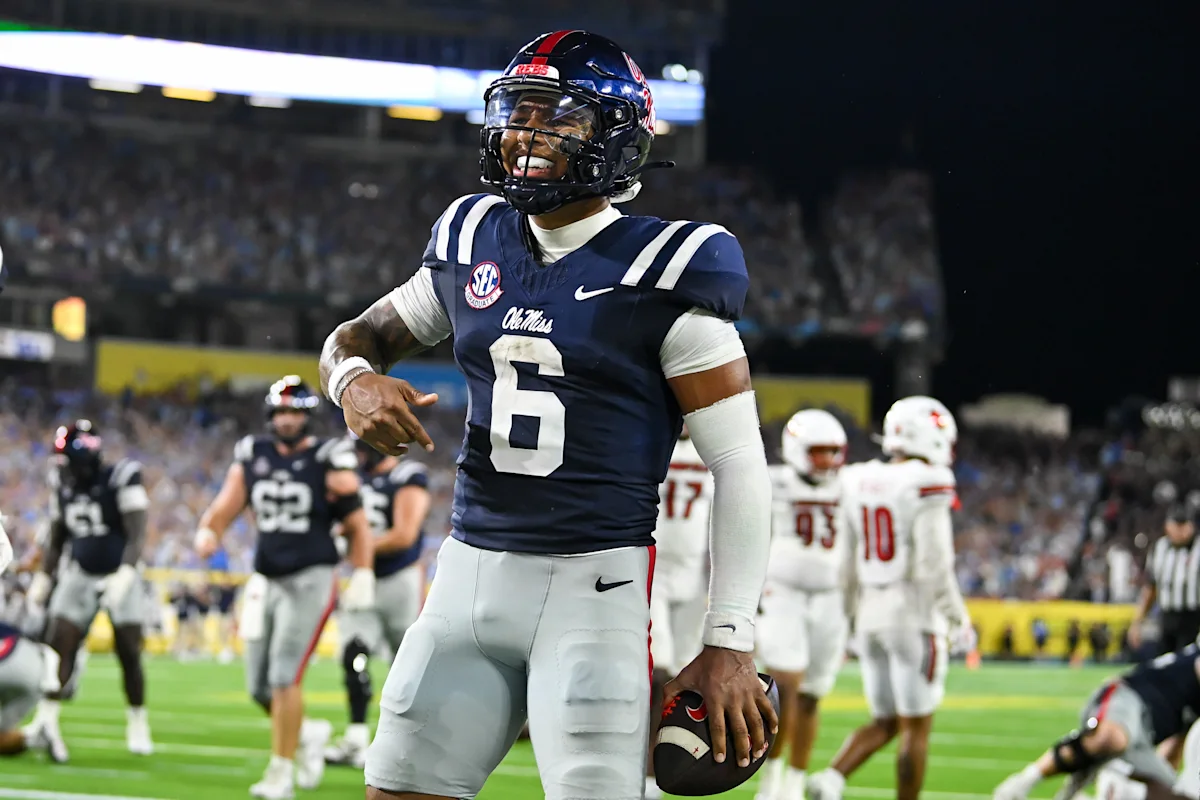 Ole Miss football player wearing number 6 celebrates on the field while holding a helmet.