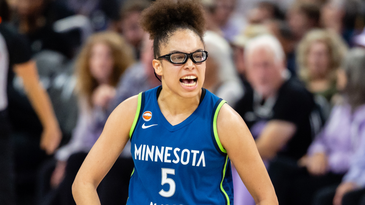 Basketball player in a blue Minnesota number five jersey and protective glasses shouts during a game.