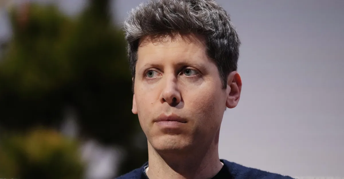 A dark-haired man in a navy top looks slightly to the side against a blurred background.
